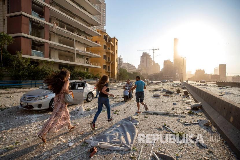  Warga berlarian dari lokasi ledakan di pelabuhan Beirut, Lebanon, Selasa (4/8) waktu setempat. Pernyataan resmi yang dirilis Kemenlu RI menyebut ada WNI yang luka akibat ledakan.