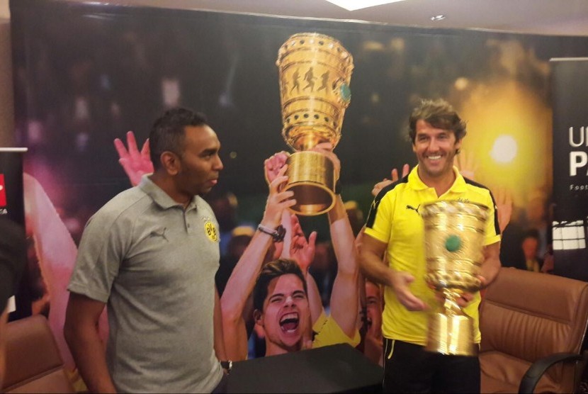 Legenda Dortmund, Karl-Heinz Riedl (baju kuning) dan Managing Director Dortmund untuk kawasan Asia, Suresh Letchmanan berfoto dengan trofi DFB Pokal 2017 di Hotel Sultan, Jakarta pada Selasa (10/10) pagi WIB. Dortmund mengunjungi Jakarta untuk merangkul pecinta sepak bola di IndonesiaR