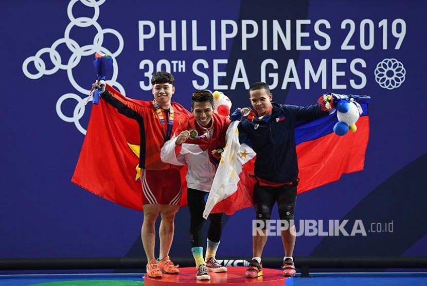 Lifter Indonesia Deni (tengah) memegang medali emas bersama lifter Vietnam Dinh Xuan Hoang (kiri) dan lifter Filipina Colona Nestor seusai upacara penganugerahan juara Angkat Besi 67Kg Putra SEA Games ke-30 di Stadion RSMC Nino Aquino, Manila, Filipina, Selasa (3/12)