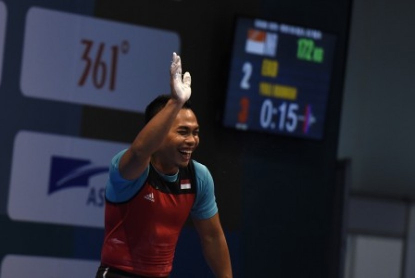 LIfter Indonesia Eko Yuli Irawan melambai usai melakukan angkatan clean and jerk pada nomor putra 62 kg 18th Asian Games Invitation Tournament di JiExpo, Jakarta, Ahad (11/2). 