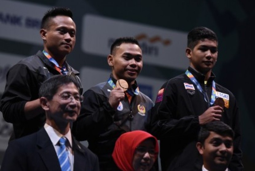 LIfter Indonesia Eko Yuli Irawan (tengah) bersama Muhamad Purkon (kiri) dan lifter Thailand Jettarin Sriram menunjukkan medali yang mereka dapat pada nomor putra 62 kg 18th Asian Games Invitation Tournament di JiExpo, Jakarta, Ahad (11/2). 