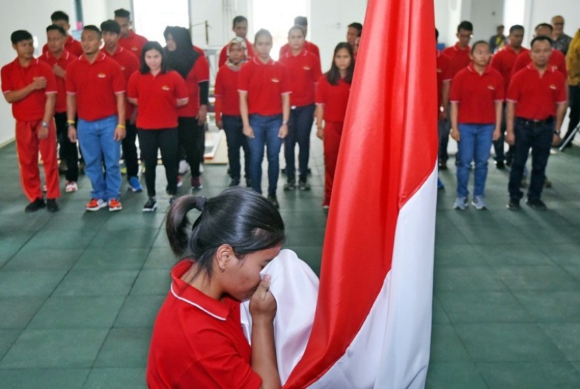 Lifter pelatnas Asian Games Indonesia Sri Wahyuni mencium bendera dalam acara pembacaan ikrar dan kebulatan tekad atlet di Jakarta, Senin (8/1). Cabang angkat besi ditargetkan meraih satu medali emas dalam Asian Games 2018.