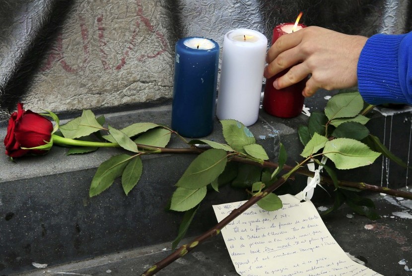 Lilin berwarna bender Prancis diletakkan dekat Bataclan, sebagai simbol duka, di pagi setelah teror terjadi, Jumat malam (13/11).