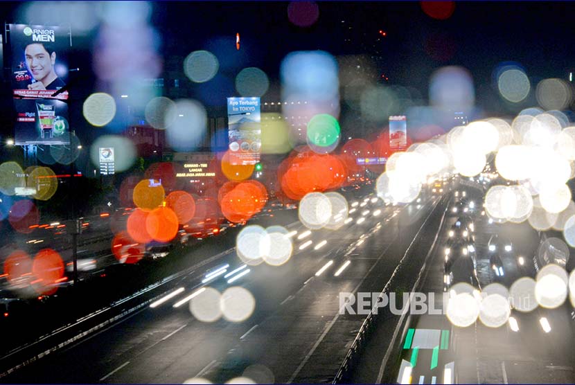 Lintasan sinar lampu mobil berpadu dengan lansekap kota malam hari di salah satu sudut kota Jakarta.