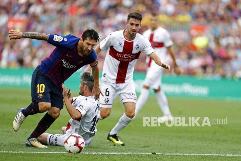 Lionel Messi berebut bola dengan pemain SD Huesca pada  pertandingan sepak bola La Liga Spanyol (2/9).