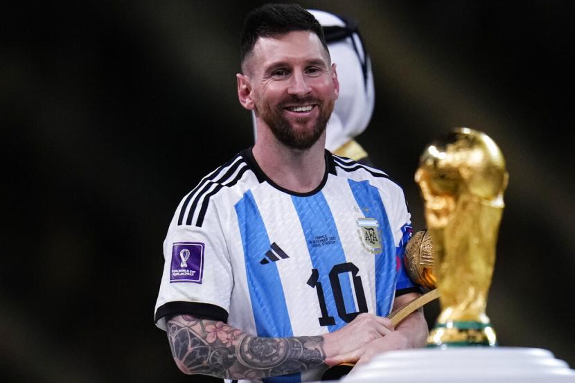  Lionel Messi dari Argentina melihat trofi setelah memenangkan pertandingan sepak bola final Piala Dunia antara Argentina dan Prancis di Stadion Lusail di Lusail, Qatar, Ahad (18/12/2022).
