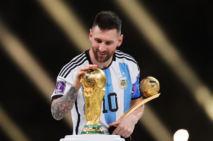  Lionel Messi dari Argentina menyentuh trofi Piala Dunia saat ia melewatinya setelah memenangkan penghargaan bola emas selama upacara penghargaan setelah Final Piala Dunia FIFA 2022 antara Argentina dan Prancis di stadion Lusail, Qatar,  Ahad (18/12/2022).
