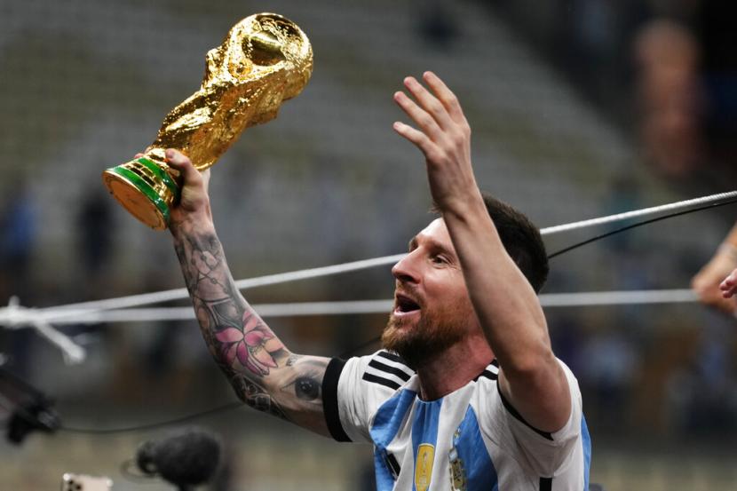 Lionel Messi dari Argentina merayakan dengan trofi setelah memenangkan pertandingan sepak bola final Piala Dunia antara Argentina dan Prancis di Stadion Lusail di Lusail, Qatar,  Ahad (18/12/2022).