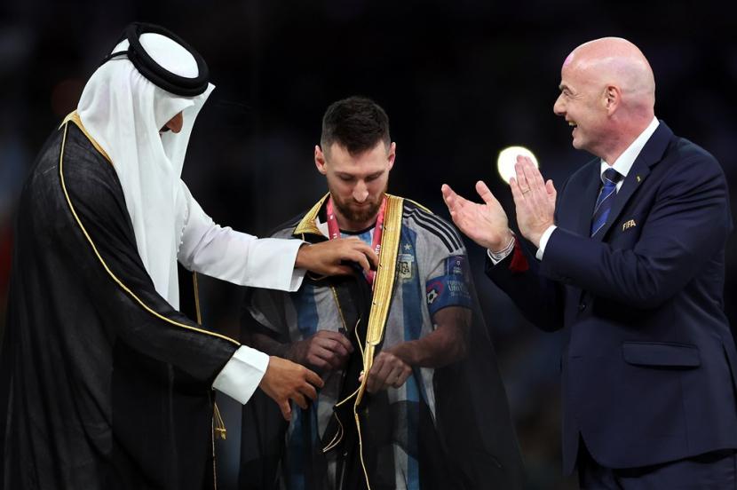  Lionel Messi dari Argentina (Tengah) menerima jubah tradisional Arab Bisht dari Tamim bin Hamad Al Thani (Kiri), Emir Qatar, saat Presiden FIFA Gianni Infantino (Kanan) melihat setelah Final Piala Dunia FIFA 2022 antara Argentina dan Prancis di stadion Lusail, Lusail, Qatar, Ahad, 18 Desember 2022. 