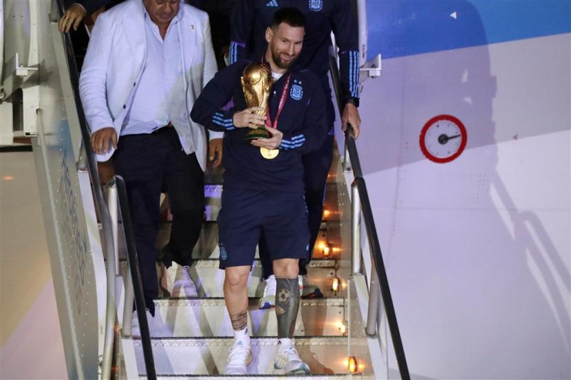  Lionel Messi dari tim sepak bola nasional Argentina turun dari pesawat dengan trofi Piala Dunia Qatar 2022 setibanya tim di Bandara Internasional Ezeiza, sekitar 22 km dari Buenos Aires, Argentina, Selasa (20/12/2022).