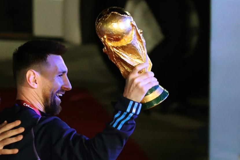  Lionel Messi dari tim sepak bola nasional Argentina memegang trofi Piala Dunia Qatar 2022 setibanya tim di Bandara Internasional Ezeiza, sekitar 22 km dari Buenos Aires, Argentina,  Selasa (20/12/2022).