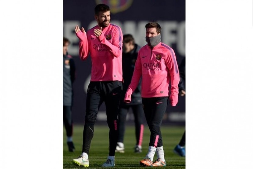 Lionel Messi (kanan) bersama Gerard Pique dalam sesi latihan Barcelona akhir tahun lalu. 