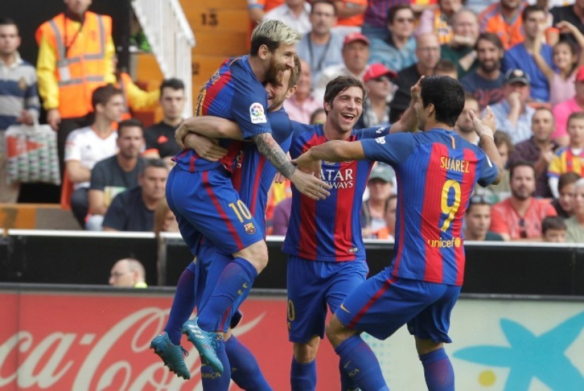 Lionel Messi (kanan) merayakan golnya ke gawang Valencia bersama rekan-rekannya.