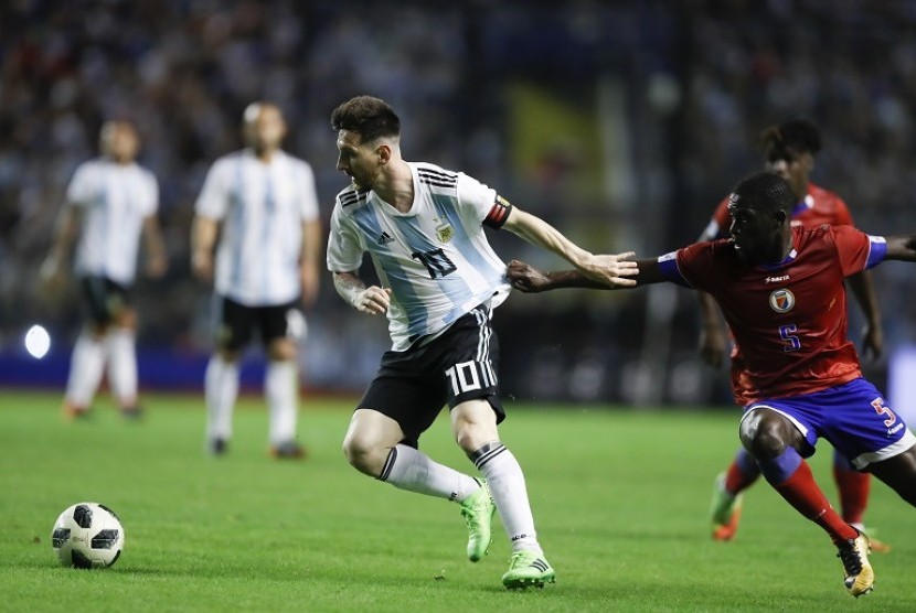 Lionel Messi (kiri) berusaha melewati pemain Haiti, Carlen Arcus, dalam laga persahabatan di Buenos Aires, Rabu (30/5) pagi WIB.
