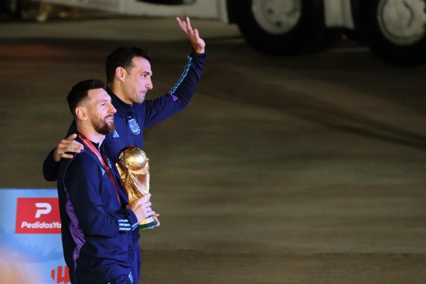  Lionel Messi (kiri) dari tim sepak bola nasional Argentina dan pelatih kepala Lionel Scaloni berpose dengan trofi Piala Dunia 2022 Qatar setibanya di Bandara Internasional Ezeiza, sekitar 22 km dari Buenos Aires, Argentina,  Selasa (20/12/2022).