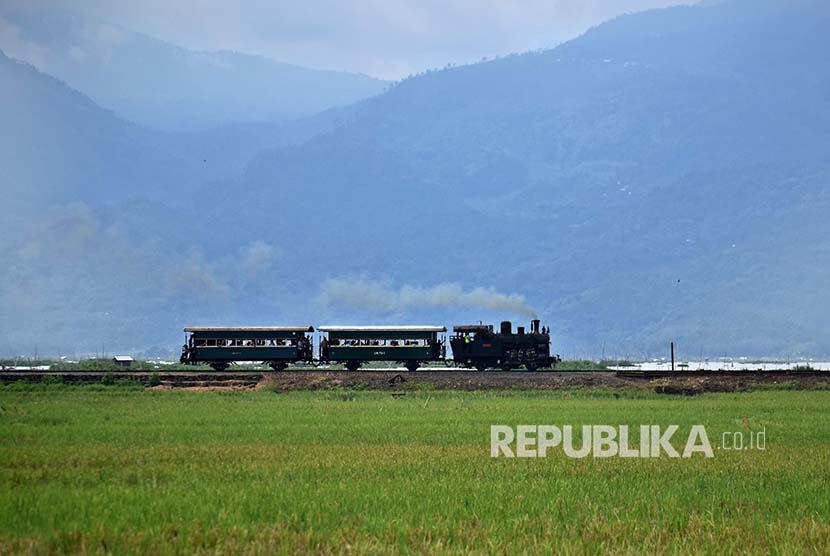 Lokomotif uap B 2503 yang menarik gerbong berisi wisatawan melaju di perlintasan kereta api di Bawen, Kabupaten Semarang, Jawa Tengah.