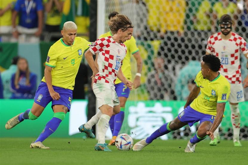  Luka Modric (Tengah) dari Kroasia beraksi melawan Eder Militao (kanan) dari Brasil selama pertandingan sepak bola perempat final Piala Dunia FIFA 2022 antara Kroasia dan Brasil di Stadion Education City di Doha, Qatar, Jumat (9/12/2022).