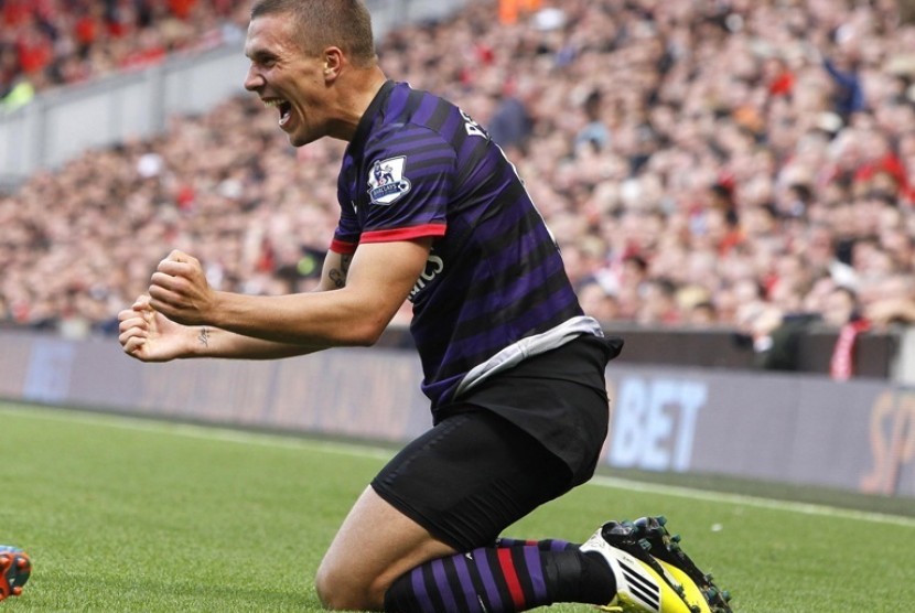 Lukas Podolski merayakan gol perdananya ke gawang Liverpool di Anfield, Ahad (2/9)