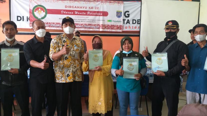  Lurah Sawangan Lama Ahsan  Haliri  (ketiga dari kiri) menyerahkan secara simbolik sertifikat tanah program PTSL  kepada enam warga, di kantor Kelurahan Sawangan, Kamis (6/1).