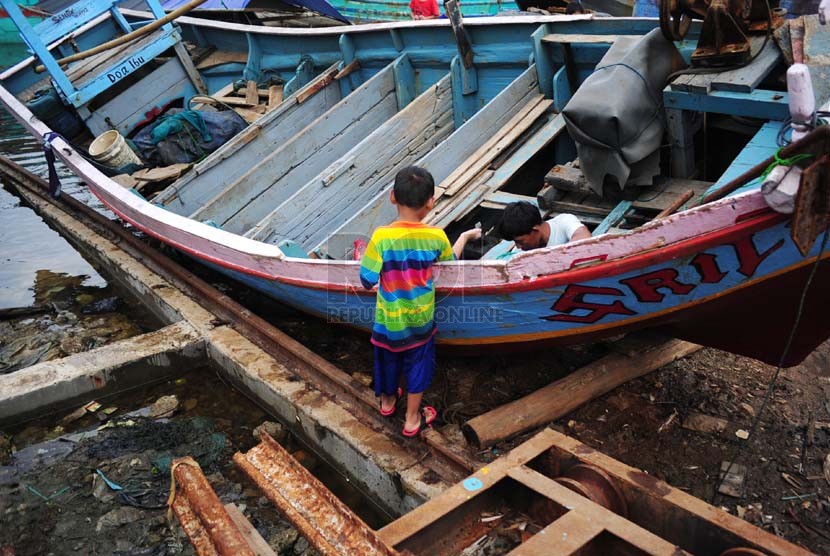 Nelayan memperbaiki kapalnya yang bersandar di Pelabuhan Muara Angke, Jakarta, Ahad (2/1).  (Republika/Adhi Wicaksono)