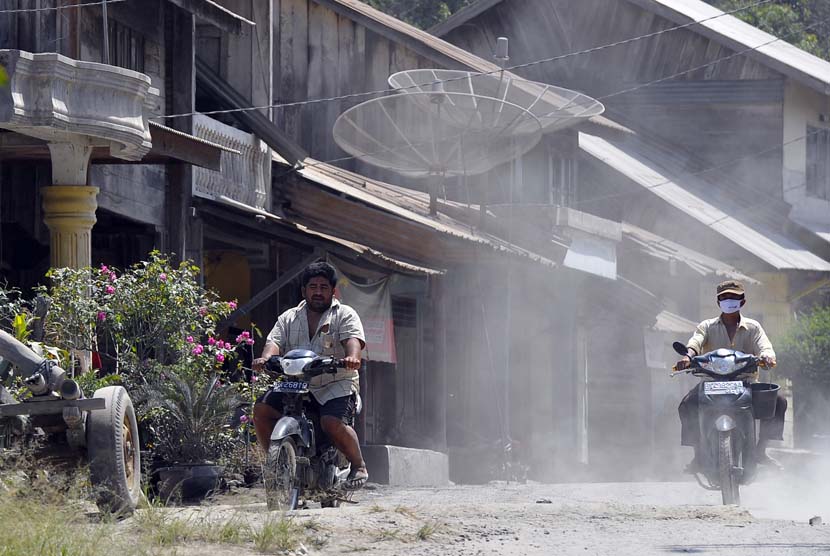   Dua warga melintasi sejumlah rumah yang diselimuti abu vulkanik Gunung Sinabung di Desa Mardinding, Karo, Sumut, Selasa (4/2).   (Antara/Wahyu Putro)