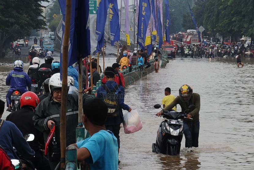 Warga berusaha menerobos genangan air di Jalan KH. Abdulah Syafei,Kampung Melayu Besar, Jakarta, Ahad (23/2). (Republika/Tahta Aidilla)
