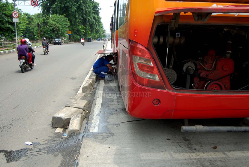  Seorang petugas memperbaiki bus TransJakarta yang mogok di Jalan Gunung Sahari Raya, Jakarta Pusat, Selasa (25/2). (foto: Raisan Al Farisi)