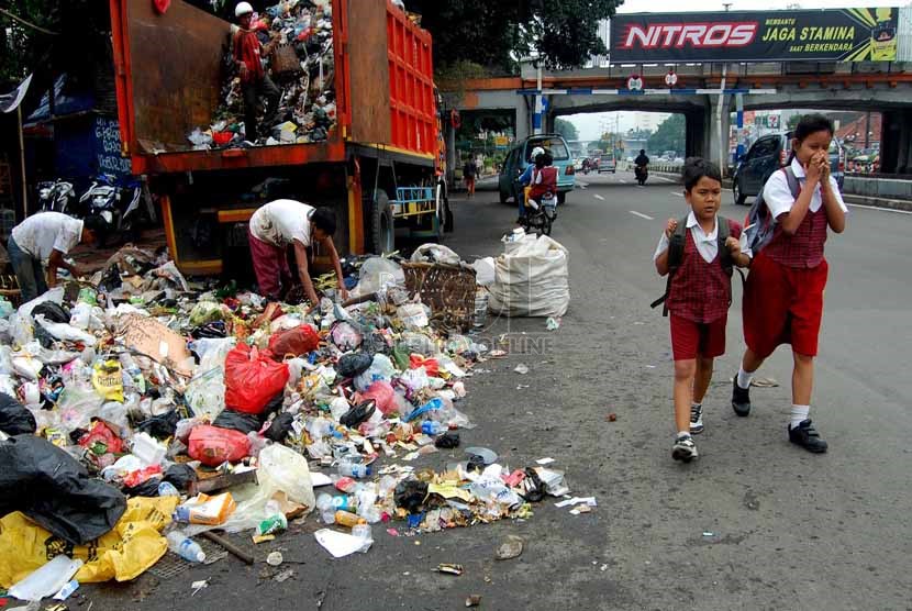   Dua orang anak melintasi sampah yang berserakan di bahu Jalan Matraman Raya, Jakarta Timur, Rabu (26/2).    (foto: Raisan Al Farisi)