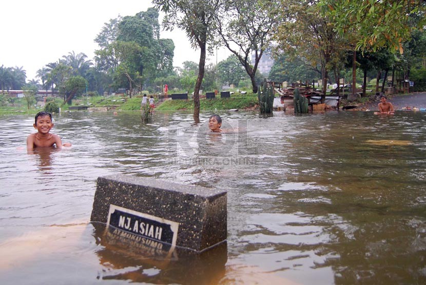   Sejumlah anak bermain air saat banjir melanda Tempat Pemakaman Umum (TPU) Karet Bivak, Tanah Abang, Jakarta Pusat, Kamis (27/2). (foto : Raisan Al Farisi)