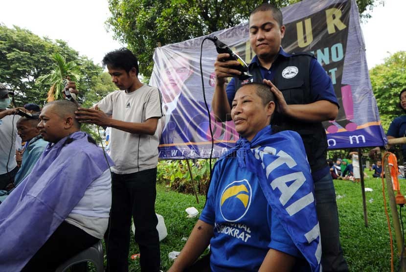  Salah seorang calon legislatif melakukan aksi potong rambut gratis dalam kampanye Partai Nasional Demokrat (Nasdem) di Kompleks Tugu Proklamasi, Jakarta, Ahad (16/3). (Republika/Aditya Pradana Putra)