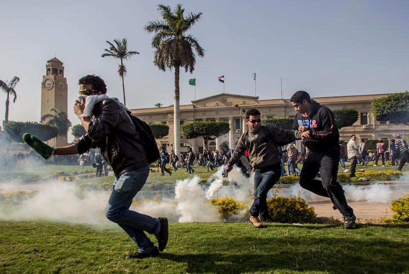  Pendukung Presiden terguling Muhammad Mursi mengambil tabung gas air mata yang ditembakkan oleh pasukan keamanan di Universitas Kairo, Giza, Mesir, Rabu (26/3).  (AP/Amru Taha)