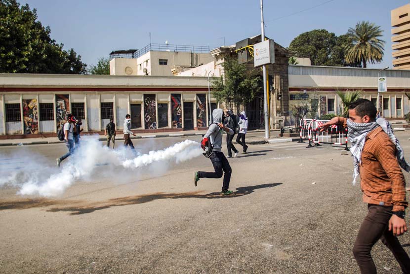  Pendukung Presiden terguling Muhammad Mursi melempar balik tabung gas air mata yang ditembakkan oleh pasukan keamanan di Universitas Kairo, Giza, Mesir, Rabu (26/3).    (AP/Amru Taha)