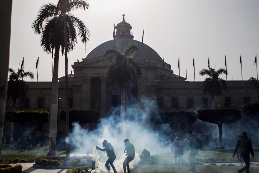 Pendukung Presiden terguling Muhammad Mursi mengambil tabung gas air mata yang ditembakkan oleh pasukan keamanan di Universitas Kairo, Giza, Mesir, Rabu (26/3).  (AP/Amru Taha)