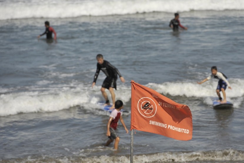   Sejumlah wisatawan berselancar di pantai meski telah dipasangi bendera larangan berenang terkait kewaspadaan dampak Tsunami Chili, di Pantai Kuta, Bali, Kamis (3/4). (Antara/Nyoman Budhiana)