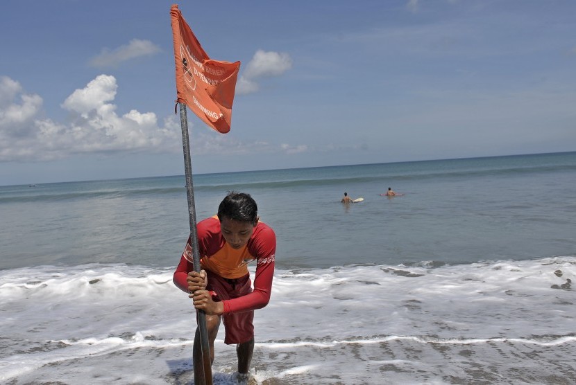  Petugas Badan Penyelamat Wisata Tirtha (Balawista) Kabupaten Badung memasang bendera rambu-rambu larangan berenang menyusul adanya seruan kewaspadaan dampak Tsunami Chili, di Pantai Kuta, Bali, Kamis (3/4). (Antara/Nyoman Budhiana)