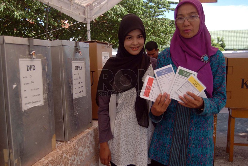  Dua orang wanita memperlihatkan kertas suara yang dipilihnya untuk dimasukan ke dalam kotak suara di TPS kawasan Blang Cut, Banda Aceh, Nanggroe Aceh Darussalam (NAD), Rabu (9/4). (Republika/Rusdy Nurdiansyah)