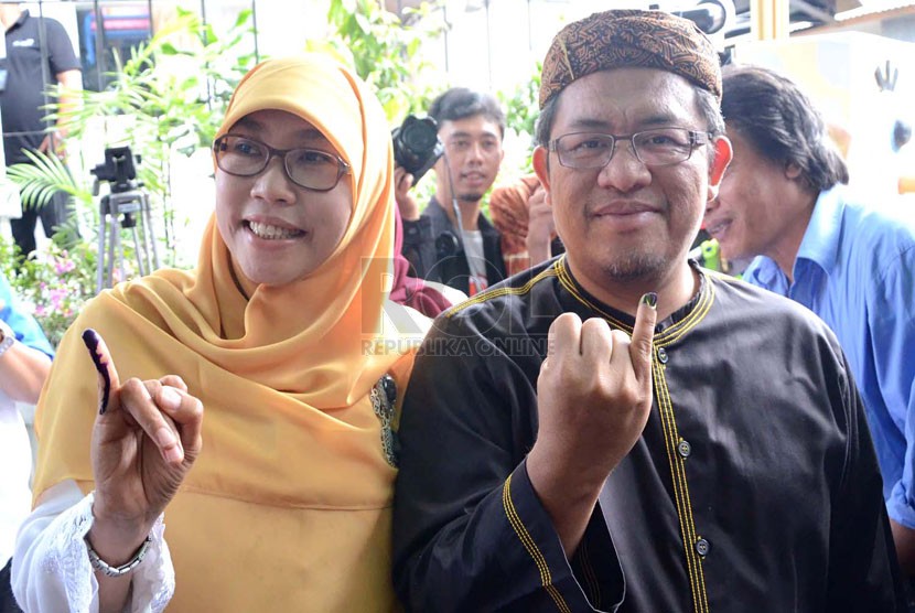 Gubernur Jabar, Ahmad Heryawan bersama istri memperlihatkan tanda tinta di kelingking usai melakukan pencoblosan di TPS 1 Keluarahan Babakan Ciamis, Bandung, Rabu (9/4). (Republika/Edi Yusuf)