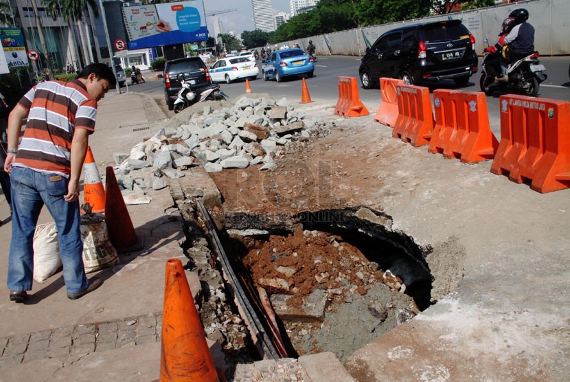  Pejalan kaki melihat lubang akibat jalan yang amblas di sekitar Halte Bus TransJakarta Polda Metro Jaya, Semanggi, Jakarta Pusat, Jumat (11/4). (Republika/Yasin Habibi)