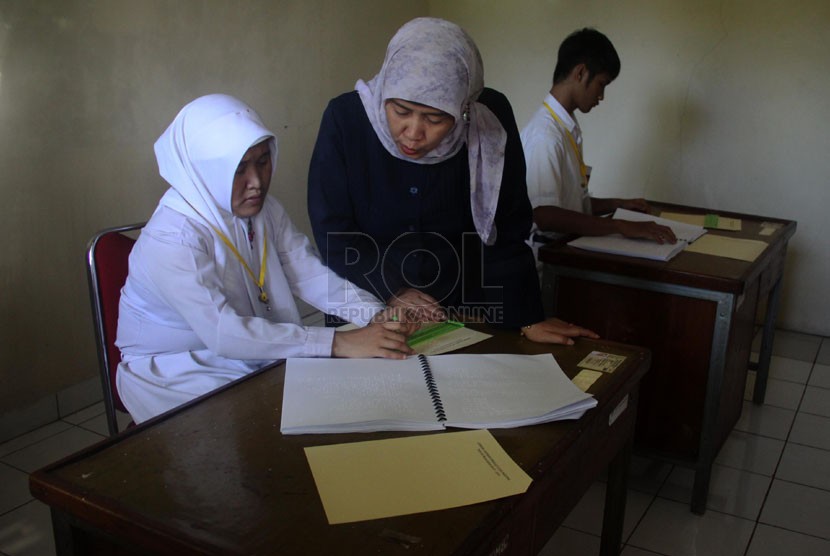   Siswa penyandang tuna netra Novitriyani (kiri), dan Ikhsanegi Ramadhan (kanan) mengikuti Ujian Nasional di SLB Bagian-A (Tuna Netra) Pembina Tingkat Nasional, Jakarta Selatan, Senin (14/4).(Republika/Yasin Habibi)