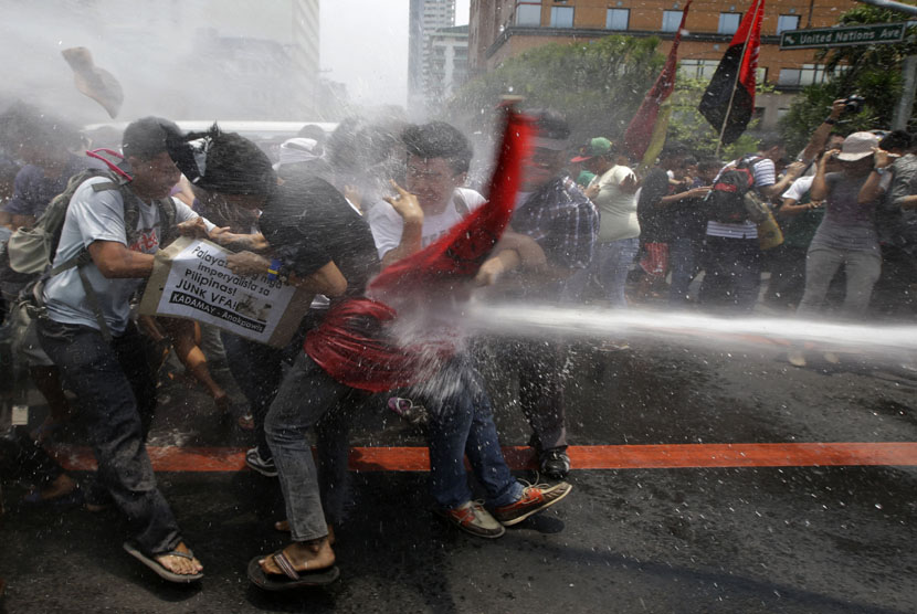  Polisi menyemprotkan air ke arah para pengunjuk rasa saat mereka memaksa mendekat ke Kedubes AS di Manila, Filipina, Rabu (23/4).  (AP/Bullit Marquez)