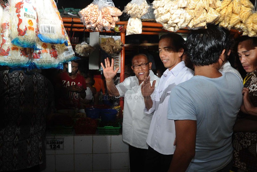 Capres dari PDIP Joko Widodo (kanan) bersama Ketua Umum DPP Partai Golkar Aburizal Bakrie (kiri) saat mengunjungi pasar Gembrong di Cempaka Putih, Jakarta, Selasa (13/5). (Republika/Tahta Aidilla)