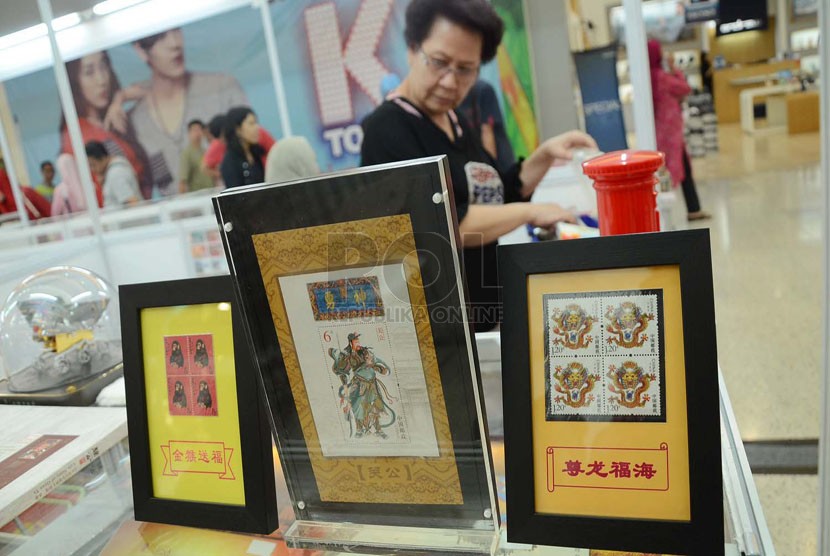   Pengunjung mengamati perangko asal luar negeri pada pameran filateli 'Four Nations Stamp Show Bandung 2014' di Festival City Link, Bandung, Selasa (27/5). (Republika/Edi Yusuf)