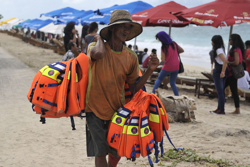 Seorang nelayan membawa pelampung kelengkapan wisata kano untuk disewakan ke wisatawan di pantai (ilustrasi)