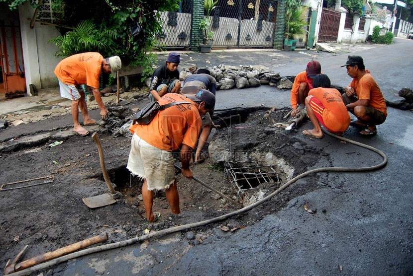  Pekerja dari Suku Dinas Tata Air Jakarta Timur memperbaiiki jalan yang amblas di Jalan Cipinang Cempedak IV, Jakarta Timur, beberapa waktu lalu.  (foto : Raisan Al Farisi)