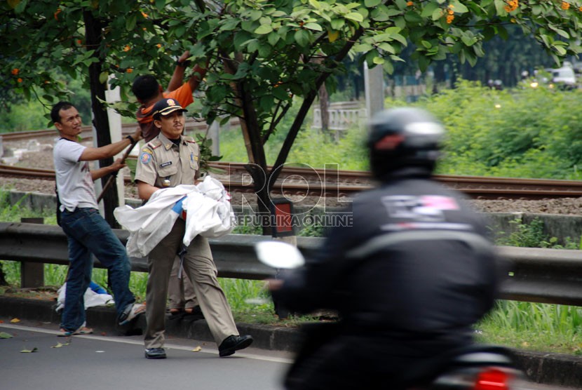 Petugas Satpol PP melepas atribut kampanye yang terpasang di Jalan Tentara Pelajar, Jakarta, Ahad (6/7). (Republika/Yasin Habibi)