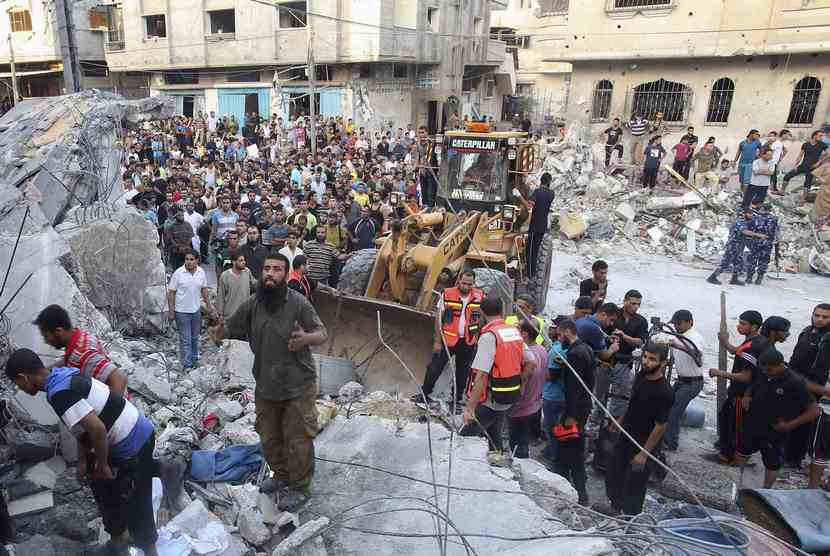  Warga Palestina bersama tim penyelamat mencari korban di bawah reruntuhan rumah yang hancur akibat serangan udara Israel di Rafah di Jalur Gaza, Jumat (11/7).  (Reuters/Ibraheem Abu Mustafa )