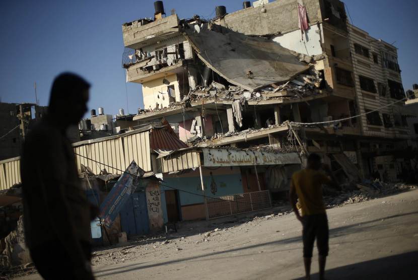  Warga Palestina menyaksikan bangunan rumah warga yang hancur akibat serangan udara Israel, di Kota Gaza, Kamis (17/7).  (Reuters/Mohammed Salem)