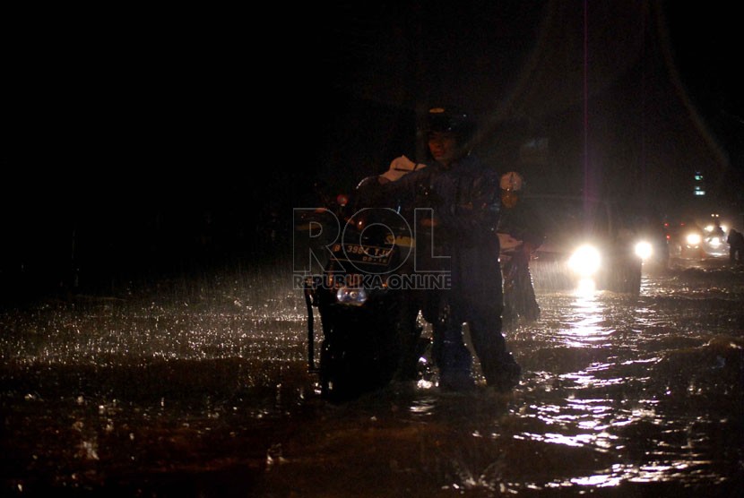  Pengendara mendorong motornya yang mogok akibat banjir di Jalan Pejaten Raya, Jakarta Selatan, Sabtu (26/7). (Republika/Raisan Al Farisi)