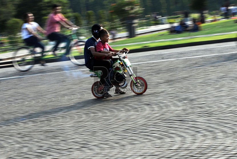   Warga menunggang permainan sepeda motor mini di Taman Silang Monumen Nasional (Monas), Jakarta, Selasa (29/7).  (Republika/Aditya Pradana Putra)