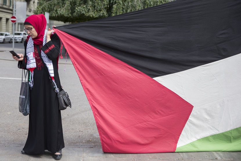 Seorang perempuan memegang bendera Palestina saat aksi protes, ilustasi